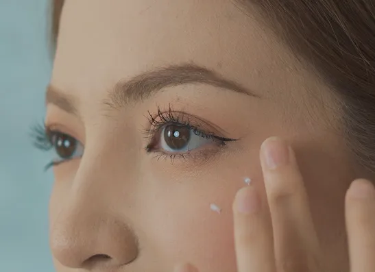 Woman applying cream under her eye